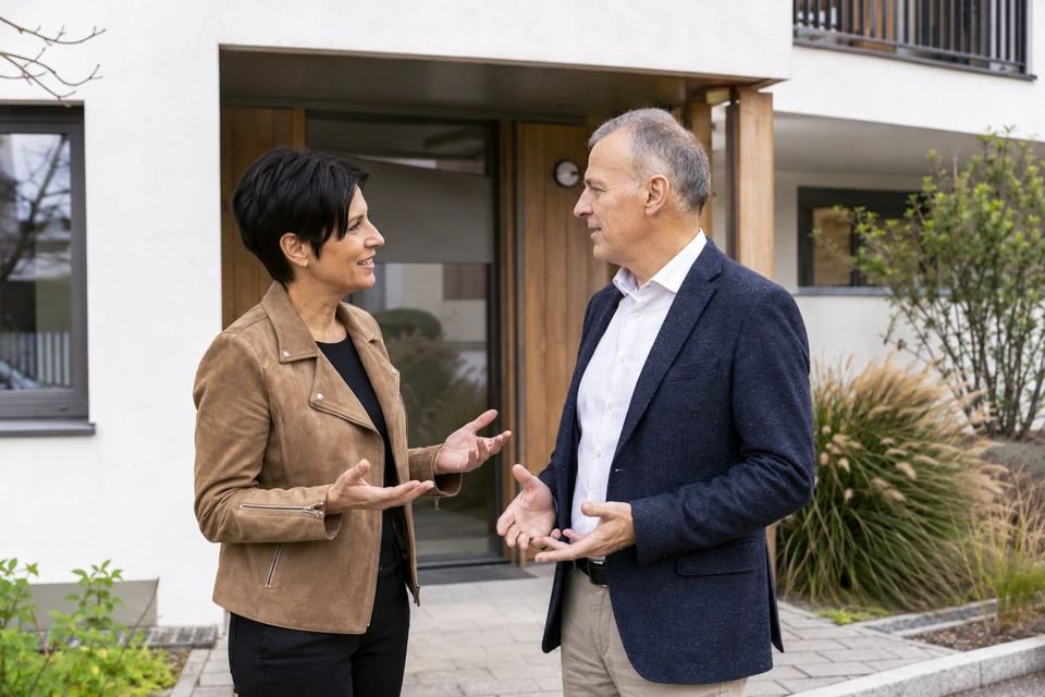 Symbolisches Eigentümergespräch vor einem österreichischen Mehrfamilienhaus